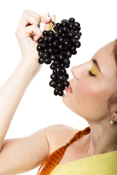 Hermosa pelirroja está comiendo uvas negras. concepto de alimentación saludable — Foto de Stock