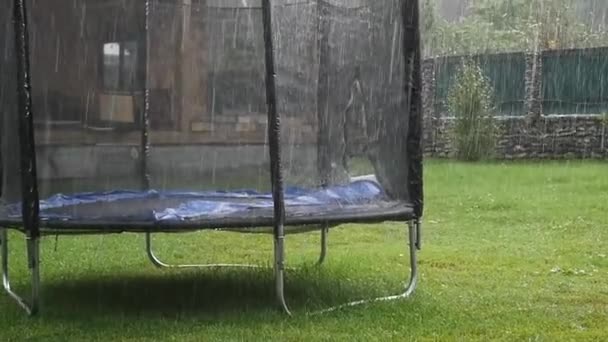 Children playground with trampoline in the rain. slow motion — Stock Video