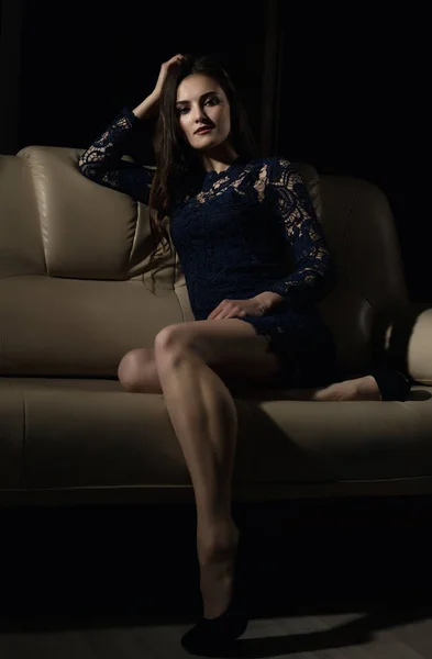 Érzéki vonzó fiatal nő, egy csipke ruha jelent a kanapén. — Stock Fotó