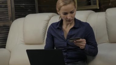 Ev ve alışveriş bir kanepede oturan güzel kadın online dizüstü bilgisayar kullanan ve kredi kartı banka. 4k