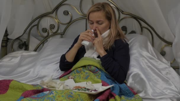 Kobieta odrobiny lek w nosie. spray do nosa. Dziewczyna leży w łóżku z ciepły szalik wokół szyi. zwolnionym tempie — Wideo stockowe