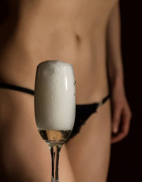 Sexy tělo žena v černém prádle nalévá šampaňské ve skle — Stock fotografie