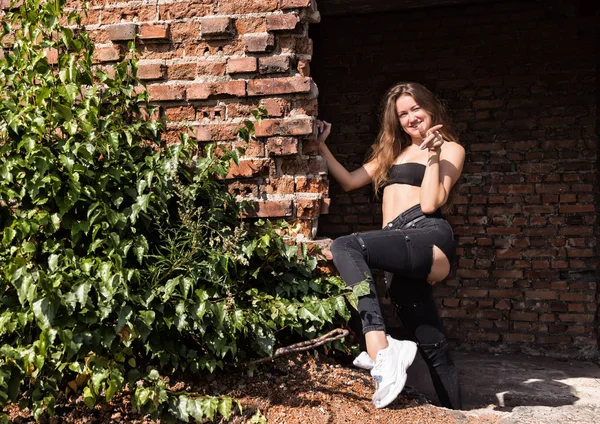 Bella giovane donna in piedi vicino al muro di mattoni in edificio abbandonato — Foto Stock