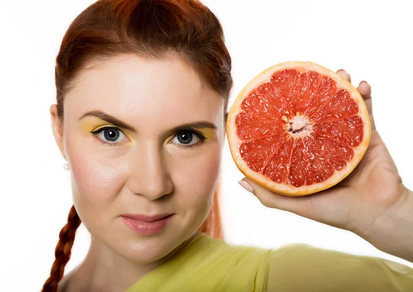 Jonge roodharige vrouw met grapefruit in haar handen studio portret op een witte achtergrond. begrip van gezond eten — Stockfoto