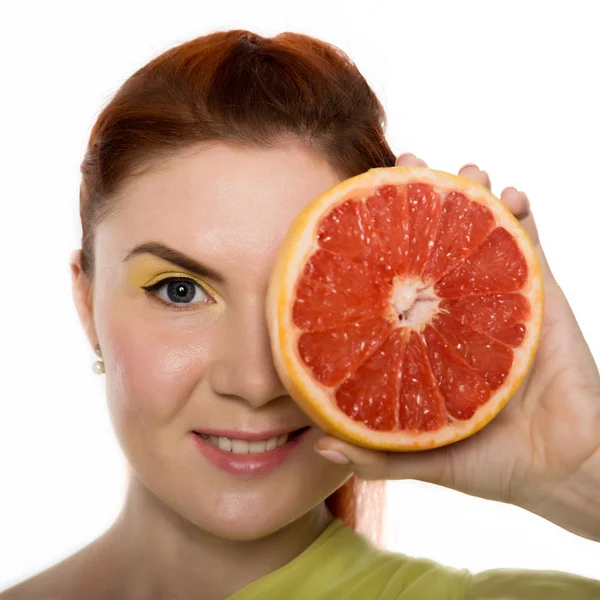 Mujer pelirroja joven con pomelo en sus manos retrato de estudio sobre un fondo blanco. concepto de alimentación saludable — Foto de Stock