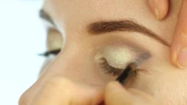 Estilista mujer pone sombra de ojos oscuros en los párpados de una novia rubia con un cepillo especial. maquillaje de boda. cámara lenta — Vídeos de Stock