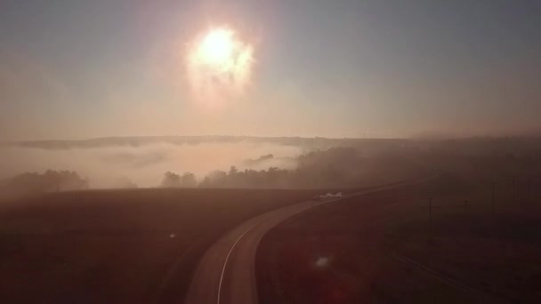 Шосе дороги в туманному сході сонця і силуеті автомобіля — стокове відео