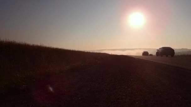Carretera carretera en nebuloso amanecer y silueta de coche — Vídeo de stock