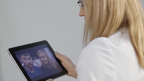 Läkare rapporterar resultaten av läkarundersökningen av videochatt med ett gift par. on-line medicin. 4k — Stockvideo