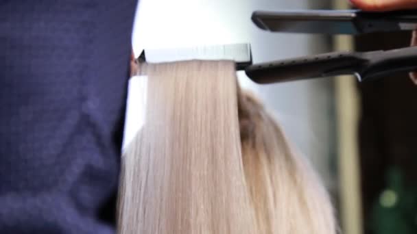Профессиональный парикмахер сделать прическу. женщина с выпрямленными волосами в парикмахерской — стоковое видео