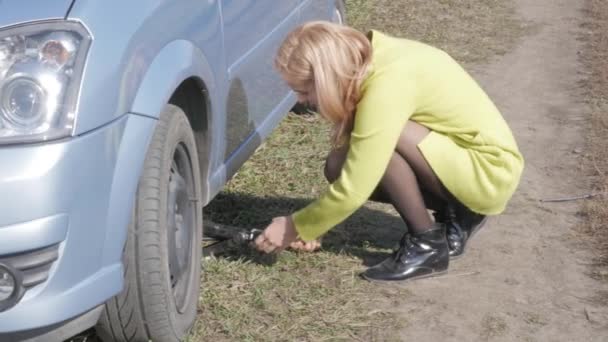 Triste encantadora joven levantando coche roto con tornillo de gato en la carretera rural. 4K — Vídeos de Stock