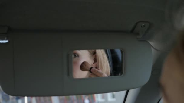 Young glamorous woman is fixing her makeup in a car looking to rearview mirror. slow motion — Stock Video