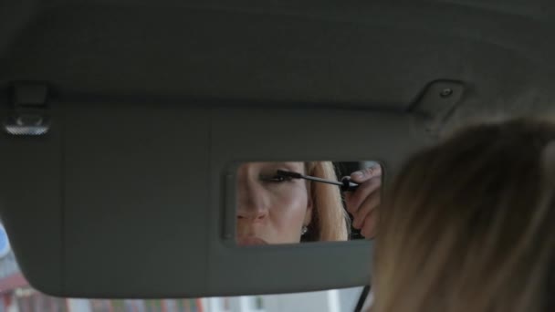 Glamorösa kvinna målar ögonbrynen i en bil ser att backspegeln. slowmotion — Stockvideo