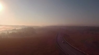 Otoban yol sisli gündoğumu ve araba silüeti. ağır çekim