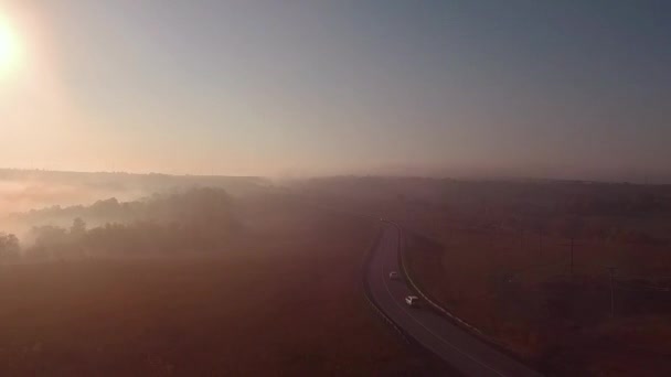 Carretera carretera en nebuloso amanecer y silueta de coche. cámara lenta — Vídeo de stock