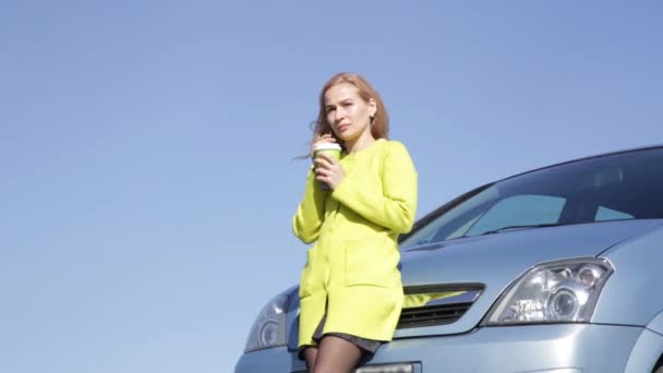 Zeker jonge zakenvrouw met kop koffie in de buurt van haar auto eist op mobiele telefoon. — Stockvideo