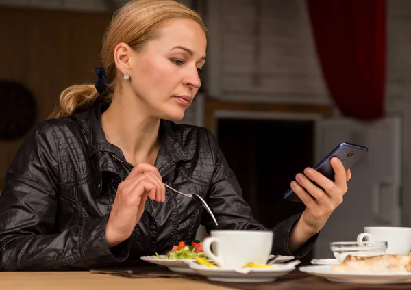 Almuerzo en un café al aire libre. empresaria comer ensalada y cheques de correo electrónico en su teléfono —  Fotos de Stock