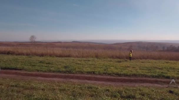 Vista aérea. mujer rubia en un camino rural de otoño cerca de coche roto. 4K — Vídeo de stock