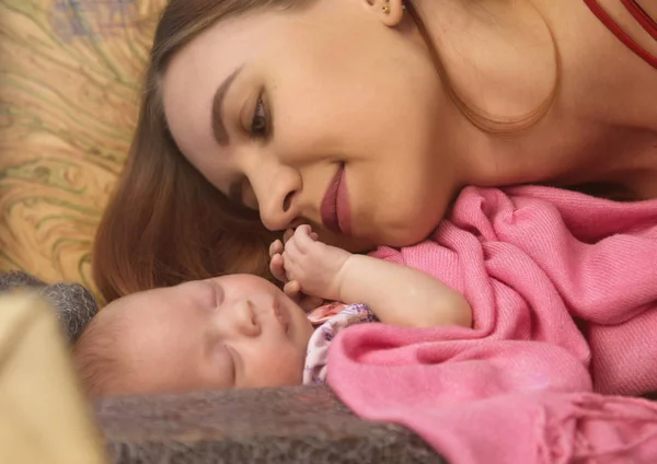 特写漂亮的女人亲吻一个新生儿在她的怀里 — 图库照片