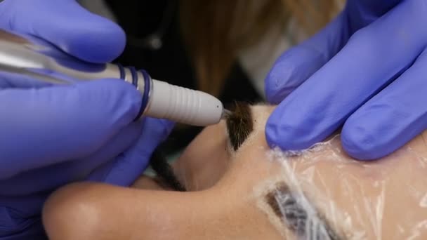 Mujer hermosa joven conseguir tatuaje de las cejas. maquillaje permanente para las cejas en el salón de belleza. cámara lenta — Vídeos de Stock