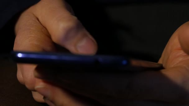 Закрыть женские пальцы используют смартфон ночью. девушка просматривает интернет на мобильном телефоне. 4K — стоковое видео