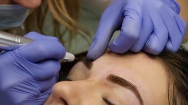 yakın çekim eller ustanın kaşları dövme yapıyor. kalıcı kaş makyaj. ağır çekim