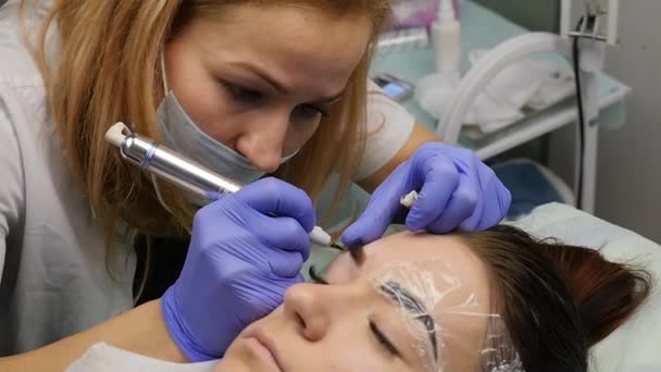 Mãos close-up do mestre fazendo tatuagem sobrancelhas. Maquiagem permanente de sobrancelha profissional. câmara lenta — Vídeo de Stock