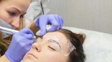 Güzellik uzmanı kadın istemciye kaşları dövme yapıyor. profesyonel kaş kalıcı makyaj. 4k