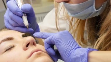 Güzellik uzmanı kadın istemciye kaşları dövme yapıyor. profesyonel kaş kalıcı makyaj. 4k
