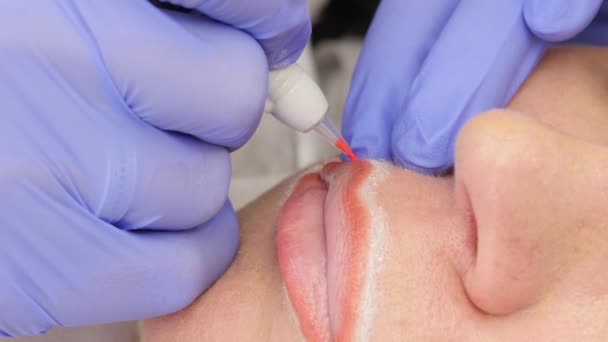 La aplicación de rojo permanente maquillaje tatuaje en los labios de las niñas. 4K — Vídeo de stock