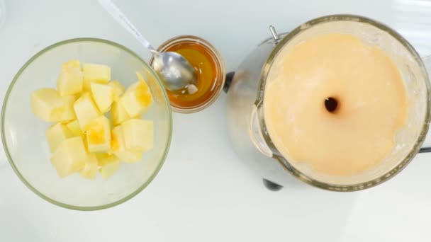 Προετοιμασία ενός κοκτέιλ φρούτων με μέλι σε ένα μπλέντερ, smoothies. Το Top view. Γυμναστήριο και έννοια του υγιεινού τρόπου ζωής. 4k — Αρχείο Βίντεο