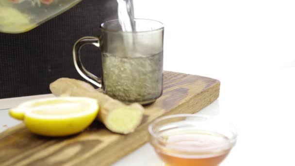 Teh dituangkan ke gelas cangkir teh transparan dengan lemon dan jahe. Pemanasan minuman dalam cuaca dingin — Stok Video