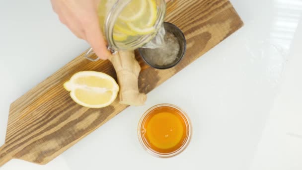 Tea being poured into glass transparent tea cup with lemon and ginger. Warming drink in cold weather — Stock Video