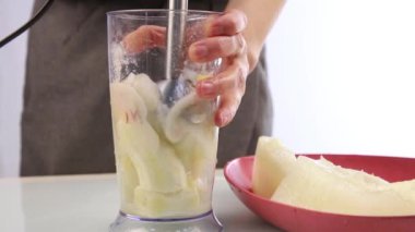 Kadın bir meyve kokteyli bir karıştırıcıda smoothies kavun ve muz ile hazırlık yapma.