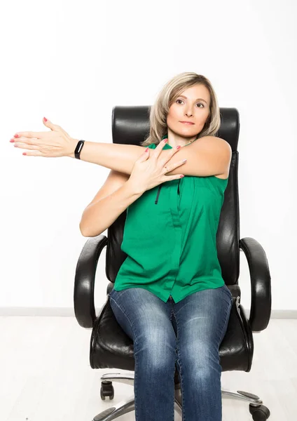 Ung affärskvinna sitter på stol gör fitness motion på arbetsplatsen — Stockfoto
