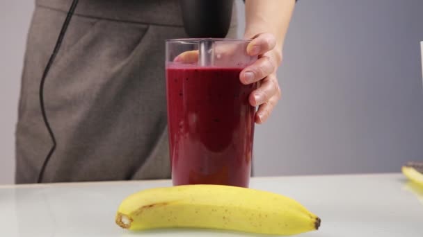 Женщина смешивает молочный ягодный коктейль в блендере, приготовление смузи — стоковое видео