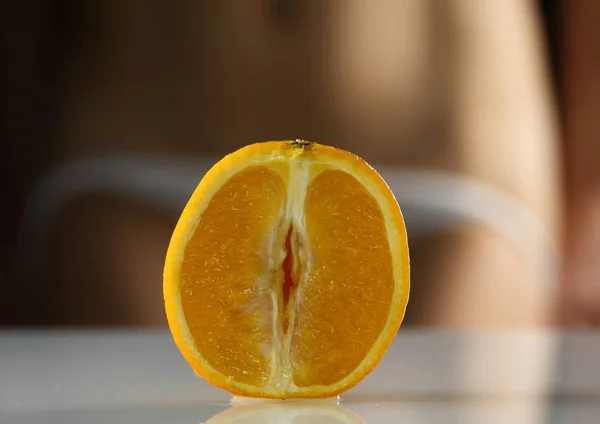 Nahaufnahme halb orange, Frau zieht ihr Höschen auf dunklem Hintergrund aus. Nachahmung der Vagina. — Stockfoto