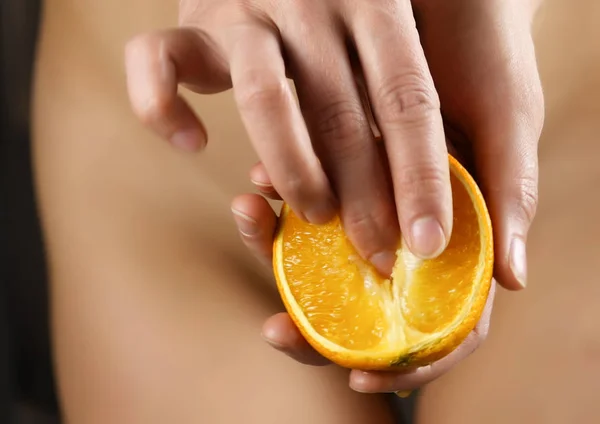 La mujer joven acaricia suavemente el trozo de naranja, el jugo gotea de la naranja. concepto de satisfacción de las mujeres necesitan —  Fotos de Stock