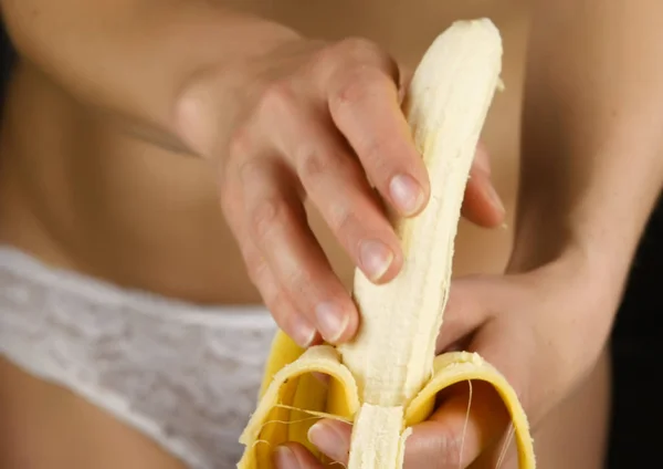 Jovem mulher descascando banana em uma calcinha branca. close-up nádegas e quadril . — Fotografia de Stock