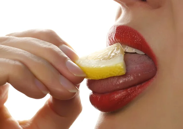 Mujer lame y comer jugoso limón, primeros labios sobre un fondo blanco . —  Fotos de Stock