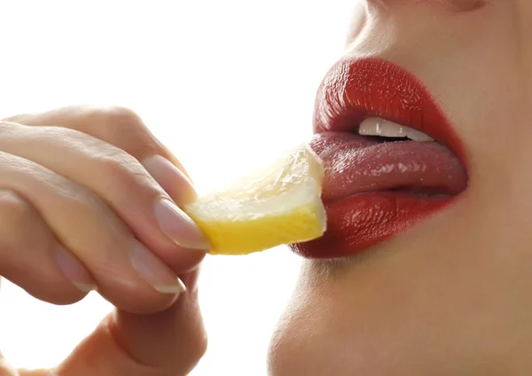 Mujer lame y comer jugoso limón, primeros labios sobre un fondo blanco . —  Fotos de Stock