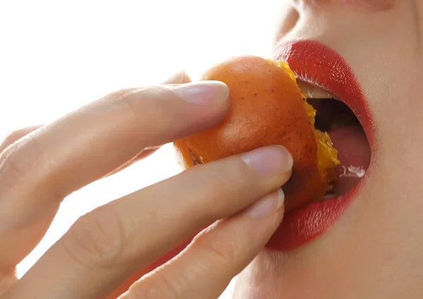 Красивая женщина облизывает и ест персик на белом фоне. крупным планом девушка кусает персик — стоковое фото