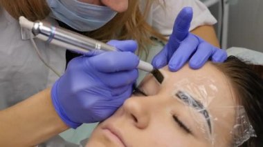 Genç güzel kadın Başlarken kaşları dövme. kalıcı makyaj Güzellik Salonu kaşları için. ağır çekim