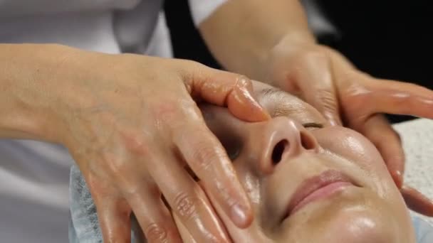 Médico feminino fazendo massagem anti-envelhecimento ao cliente. mulher gosta de massagem facial de plástico em saton spa. 4K — Vídeo de Stock