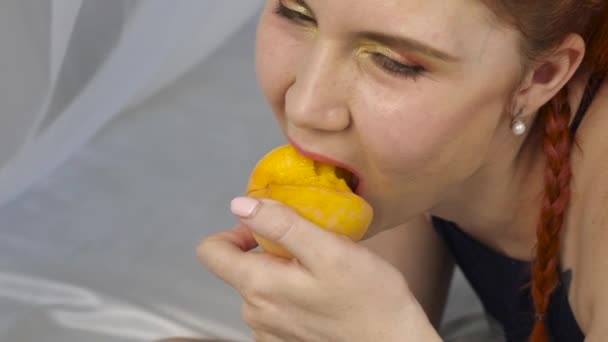 Rusovláska žena jí čerstvé ovoce vleže v posteli. Zdravá snídaně. Zpomalený pohyb — Stock video