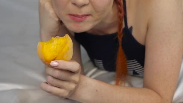 Donna rossa mangia frutta fresca mentre si trova a letto. colazione sana. rallentatore — Video Stock