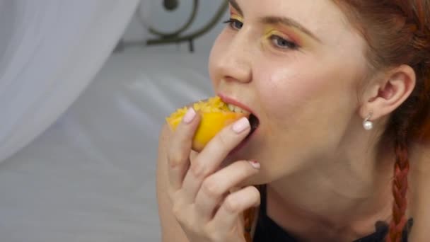 Mujer pelirroja come fruta fresca mientras está acostada en la cama. desayuno saludable. cámara lenta — Vídeo de stock