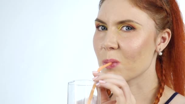 Mujer joven disfrutando y bebe jugo de naranja sobre un fondo claro. cámara lenta — Vídeos de Stock