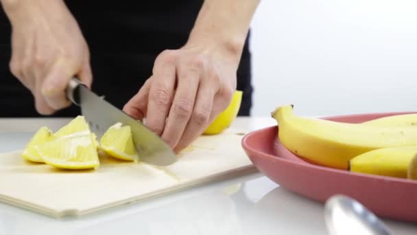 Woman cutting lemon on a wooden board on the kitchen. — Stock Video