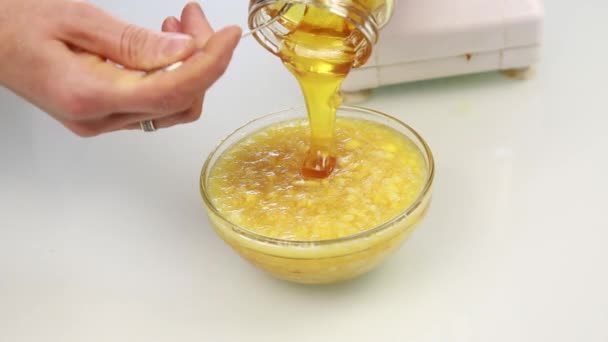 Γυναίκα ανάμειξης υλικά σε μπολ και προσθέτοντας μέλι σε ένα βούτυρο ξηρών καρπών — Αρχείο Βίντεο